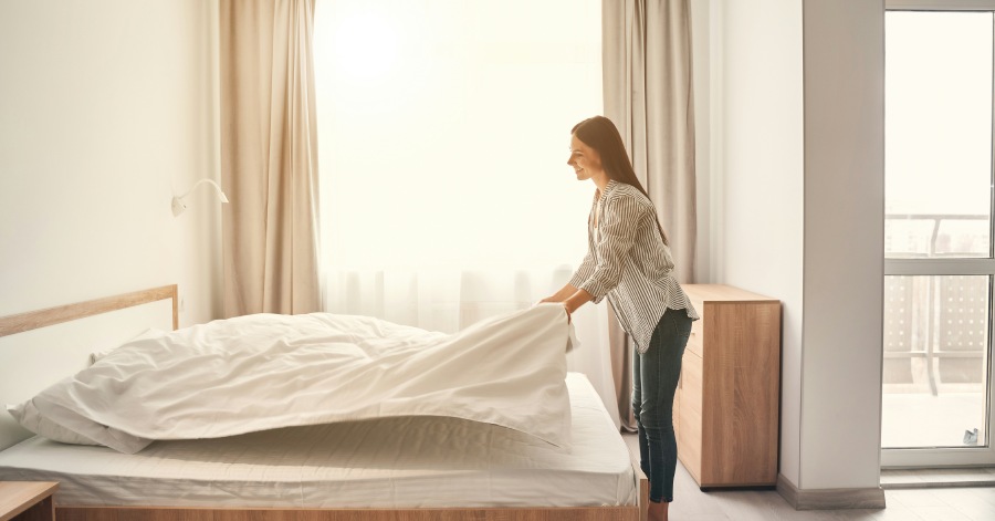 Woman making bed after sanitizing the mattress.